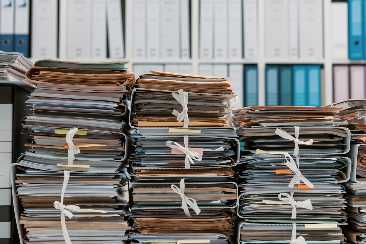 Différentes piles d'archives sous forme papier dans un espace de bureau.