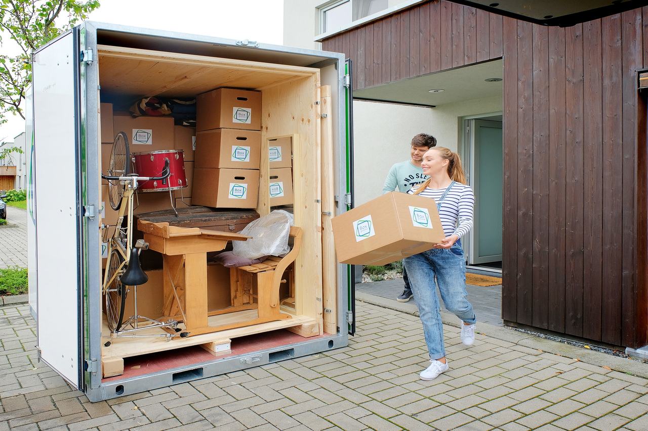 A young couple are busy loading the Large Box that is waiting at their door