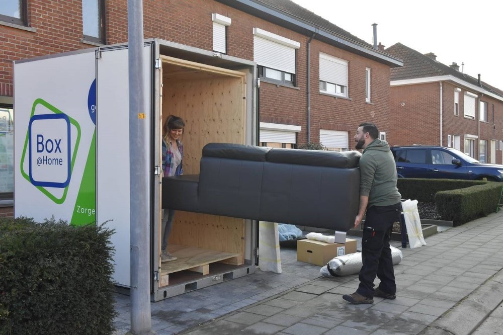 A young couple carefully put their sofa into the Large Box in front of their door