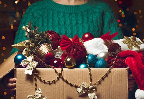 Une femme porte une boîte en carton remplie de décorations de Noël.